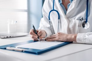 Doctor sitting at desk and writing.