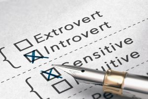A psychometric assessment paper with multiple-choice boxes labeled Extrovert, Introvert, Sensitive, Intuitive, with a pen selecting an answer.