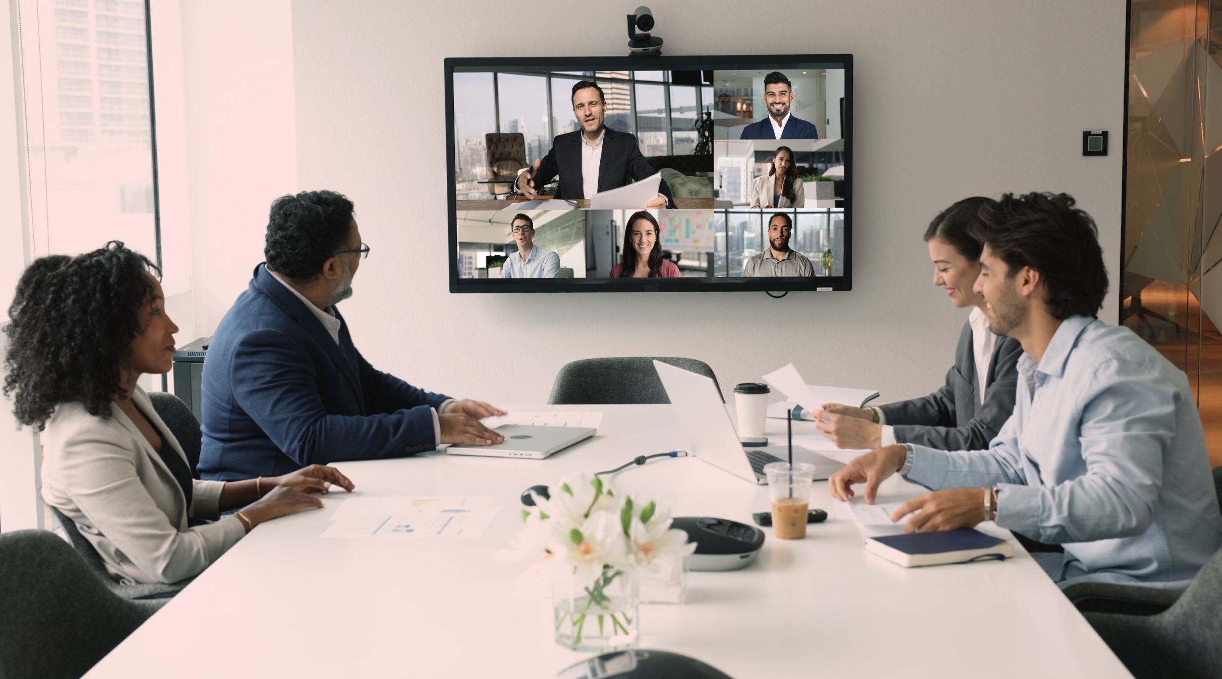 Hybrid business meeting with in-person and remote participants connected via video conferencing